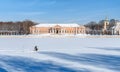 A fisherman sits on the ice of a large palace pond and catches fish.